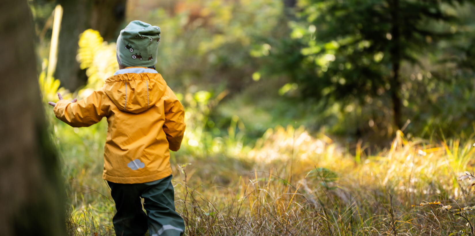 Kind von hinten, das durch den Wald läuft