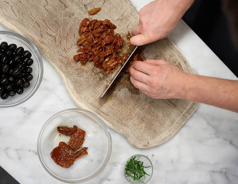 Es werden getrocknete Tomaten geschnitten.